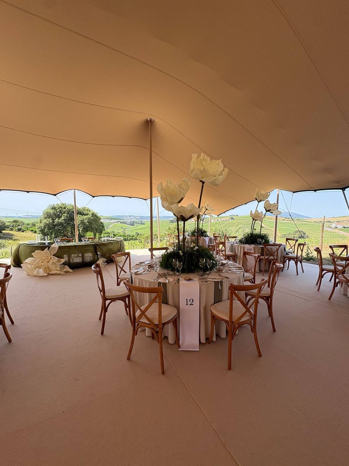 The pavilion dressed with round tables and flowers, hills beyond