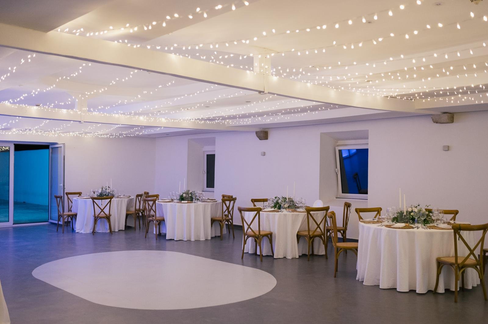 The reception hall set with round tables under fairy lights
